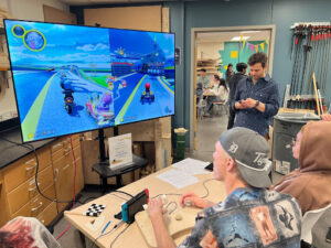 A group of people use adaptive controllers to play Mario Kart 8
