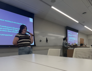 Betsy Strehl smiles with a microphone, facilitating a workshop on the Xbox Adaptive Controller and Design Accessibility 